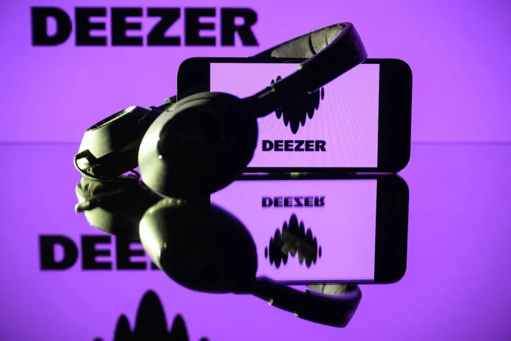 This photograph taken on January 13, 2025 in Toulouse shows headphones beside a smartphone and a computer screen displaying the logo of the French music streaming platform Deezer.
